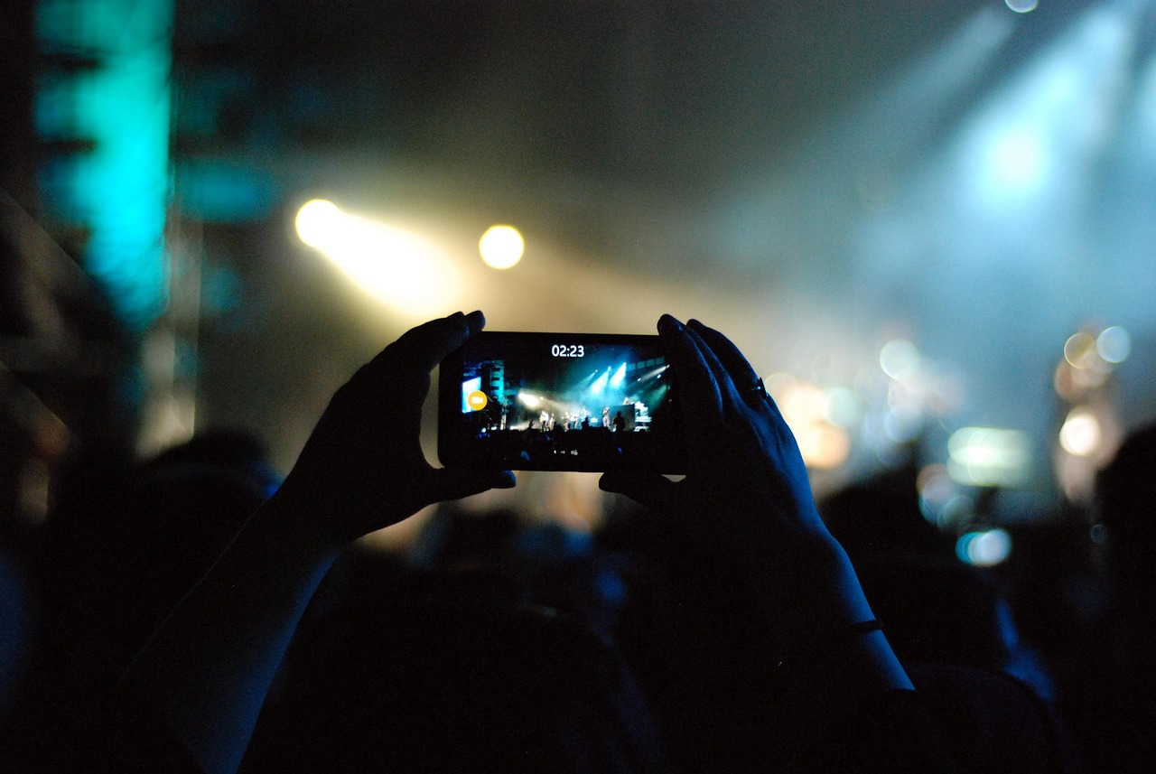 Manos grabando un concierto con un teléfono celular